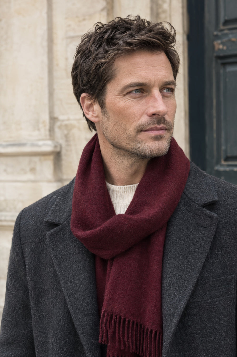 A man wearing a scarf with tailored outerwear.