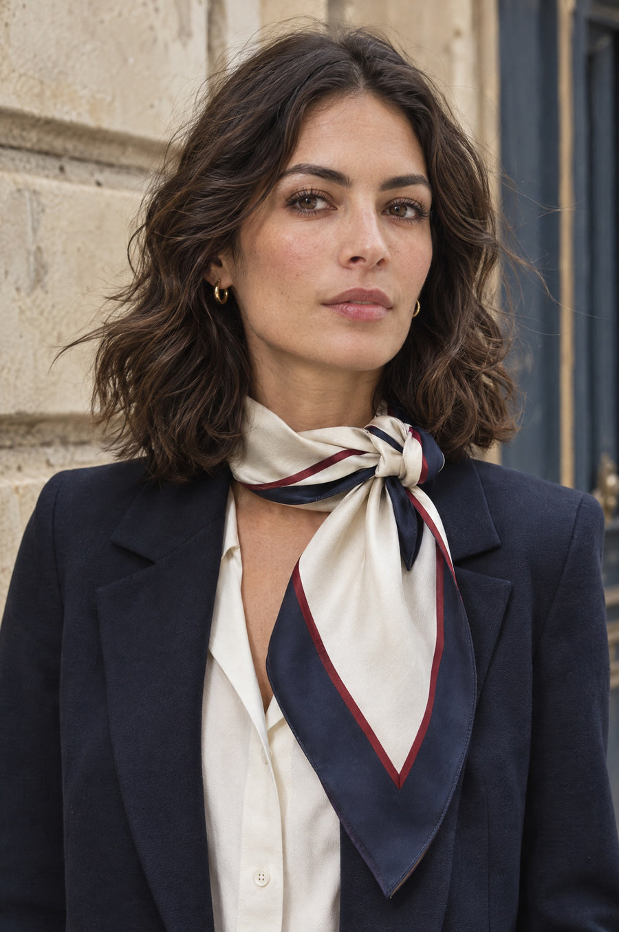 A woman wearing a silk scarf with tailored outerwear.
