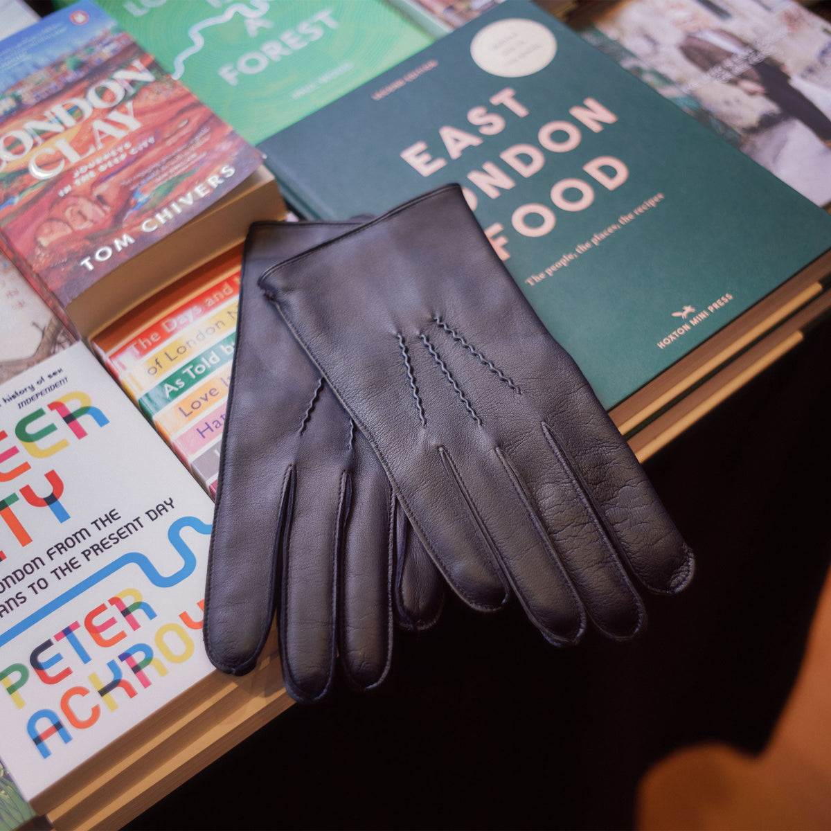 Mens navy leather gloves lying on a pile of books.